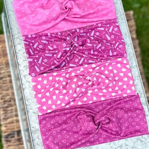 Peut inclure: Quatre bandeaux de tête à motifs roses et rouges sur le thème dentaire. Les bandeaux présentent un motif répété de dents et de brosses à dents.