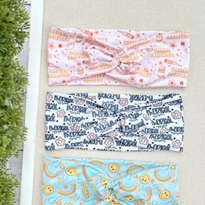 May include: Three different patterned headbands. The top headband is pink with a white pattern of medical symbols and the text "Medical Assistant". The middle headband is white with a black pattern of flowers and the text "Medical". The bottom headband is light blue with a pattern of rainbows, smiley faces, and stethoscopes.
