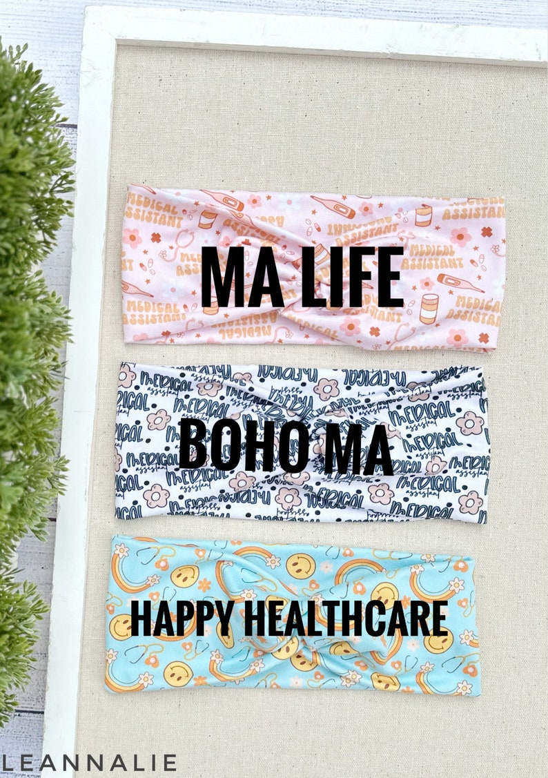 May include: Three colorful headbands with different patterns. The top headband is pink with a white pattern of medical symbols and the text "MA LIFE". The middle headband is white with a black pattern of flowers and the text "BOHO MA". The bottom headband is light blue with a yellow pattern of rainbows and smiley faces and the text "HAPPY HEALTHCARE".