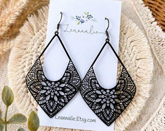 May include: A pair of black teardrop-shaped earrings featuring an intricate laser-cut floral mandala pattern. The earrings hang from dark metal hooks on a white display card printed with the text Leannalie and Leannalie.Etsy.com.