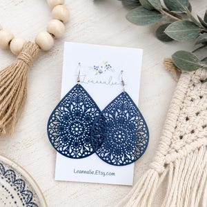 May include: Navy blue filigree teardrop earrings. The earrings have a detailed, openwork design. The earrings are displayed on a white card with the text "Leannalie.Etsy.com".
