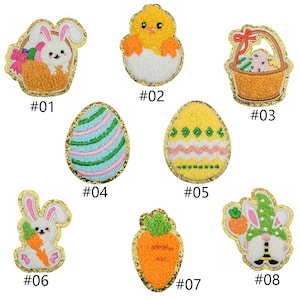 May include: Eight embroidered iron-on patches with Easter themes. The patches feature a bunny in a basket, a chick in an egg, a basket of eggs, a striped egg, a patterned egg, a bunny holding a carrot, a carrot, and a bunny wearing a hat.