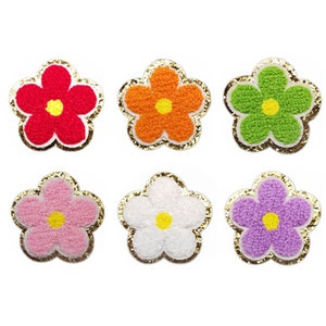 May include: Six colorful flower patches with a textured, plush appearance. Each flower has a different color: red, orange, green, pink, white, and purple. The petals are outlined with gold glitter.