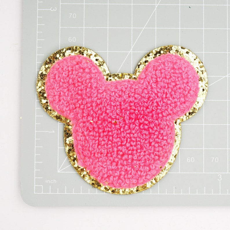 Peut inclure: Oreilles de souris en tissu rose duveteux avec une bordure dor&eacute;e paillet&eacute;e.