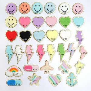 Peut inclure: Un ensemble de 59 patchs thermocollants de diff&eacute;rentes couleurs et motifs, notamment des smileys, des c&oelig;urs, des &eacute;clairs, des arcs-en-ciel, des &eacute;toiles, des avions et des ancres. Chaque patch est bord&eacute; d'un contour paillet&eacute; dor&eacute;.