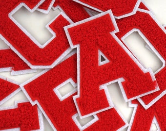 May include: Red felt letters with white outlines, spelling out the word "CAD"