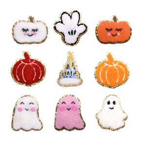 Puede incluir: Una colección de nueve parches con temática de Halloween. Los parches incluyen calabazas sonrientes en naranja, blanco y rojo, fantasmas blancos y rosas, una mano blanca de Mickey Mouse y un castillo. Cada parche tiene un borde dorado brillante.