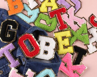 May include: Assortment of colourful felt letter patches with gold glitter trim. The letters are in various colours, including red, blue, green, yellow, pink, and orange. The patches are perfect for adding a personalised touch to clothing, bags, or other accessories.