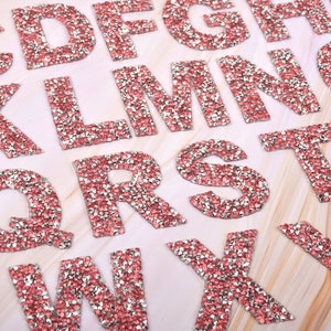 May include: Pink and silver rhinestone alphabet letters. Each letter is made of small, sparkling rhinestones.