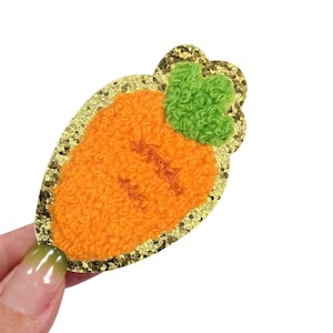 May include: A gold glitter carrot patch with a fuzzy orange carrot and green fuzzy leaves.