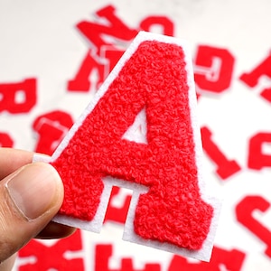 Peut inclure: Lettre A en feutre rouge avec un dos blanc. La lettre est duveteuse et a un aspect 3D.