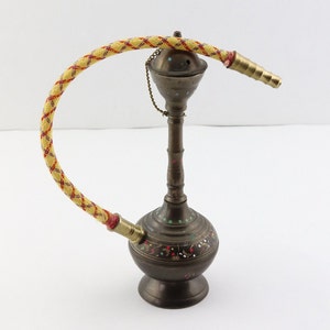 May include: A brass hookah with a yellow and red braided hose. The base of the hookah is decorated with colorful floral patterns.