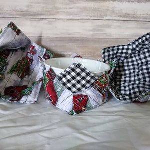 May include: Three fabric bowl cozies. One is black and white checkered, one has a red truck and Christmas tree design, and the other has a red truck and white picket fence design.