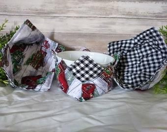 May include: Three fabric bowl cozies. One is black and white checkered, one has a red truck and Christmas tree design, and the other has a red truck and white picket fence design.