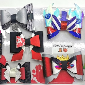 Könnte beinhalten: Eine Sammlung handgefertigter Haarschleifen in verschiedenen Designs. Die Schleifen weisen eine Mischung aus Texturen auf, darunter Glitzer, Leder und gemusterte Stoffe. Farben sind Silber, Schwarz, Rot, Weiß und Blau. Einige Schleifen haben Verzierungen wie Spikes, Anhänger und Edelsteine. Der Text "Hell Employer" ist enthalten.