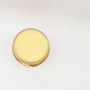 May include: A yellow candle in a clear glass jar with a twine bow.