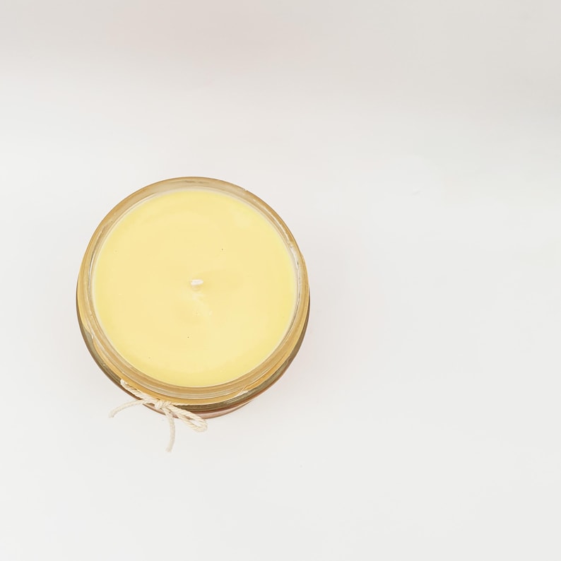 May include: A yellow candle in a clear glass jar with a twine bow.
