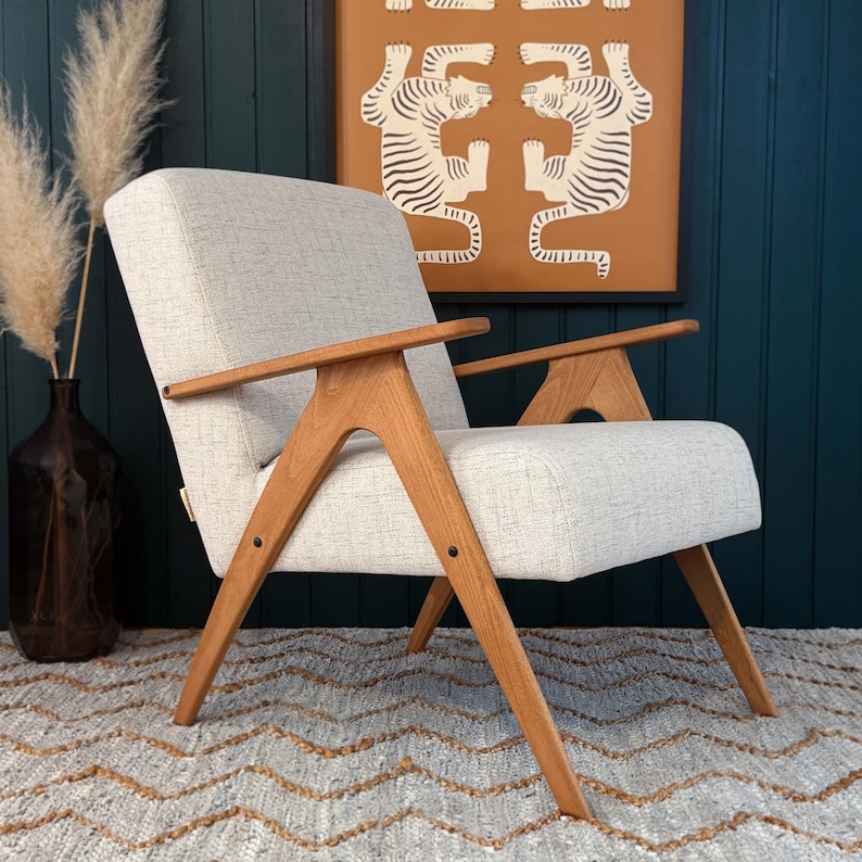 Mid-century beech armchair, beige cushion, compact footprint on accent rug against teal wall