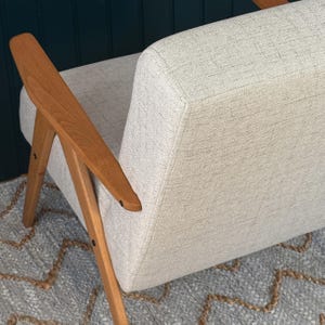 Overhead angle showing textured linen-look backrest and tapered beech arms meeting seat