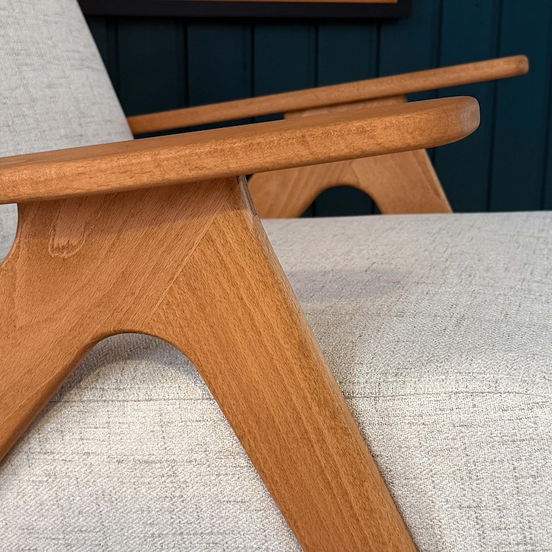 Beech armrest and sculpted leg joint with smooth grain against beige textured seat