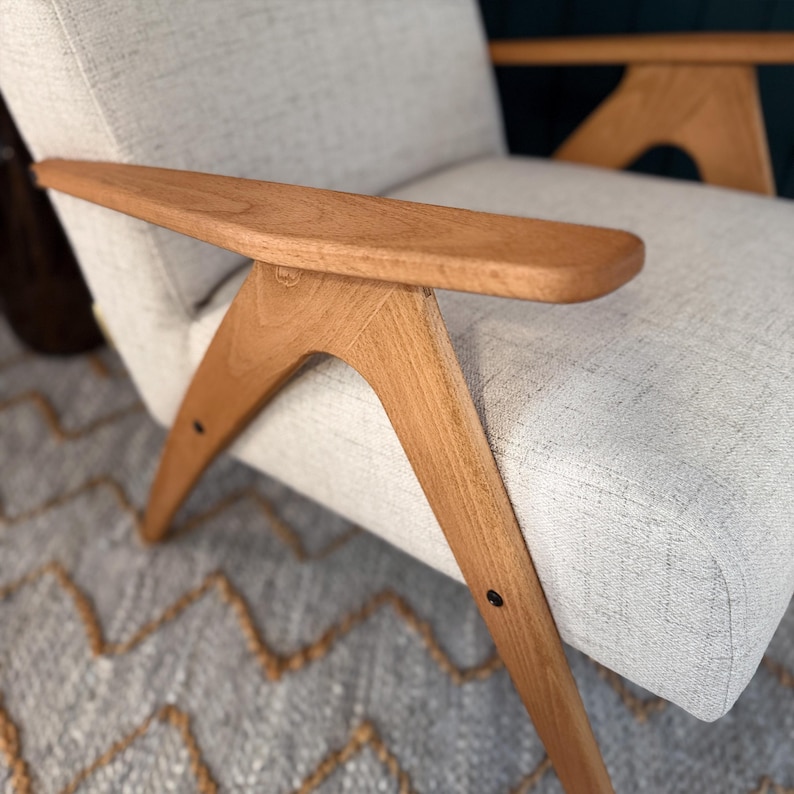 Rounded beech arm meeting leg brace and beige seat, emphasising smooth curves and joinery