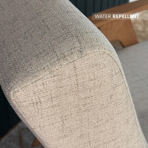 Beige textured fabric armrest labelled “water repellent” showing stain-resistant upholstery
