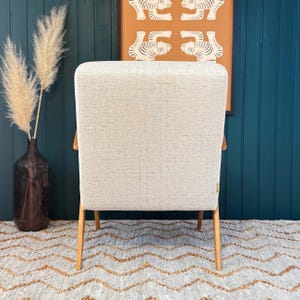 Rear view of chair showing clean beige backrest and slim tapered legs before teal panel