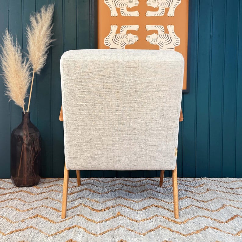 Rear view of chair showing clean beige backrest and slim tapered legs before teal panel