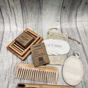 May include: A zero waste kit featuring a wooden soap dish with a bar of soap, a wooden comb, a bamboo toothbrush, reusable cotton pads in a drawstring bag, and a natural exfoliating sponge. The kit includes a card that reads "Zero Waste Kit".