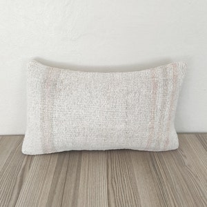 May include: A white and pink patterned throw pillow with a rectangular shape.