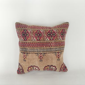 May include: A decorative pillow with a brown background and a red, black, and white geometric pattern.