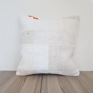 May include: White throw pillow with a patchwork design. The pillow is made of a soft, woven fabric and has a subtle texture.