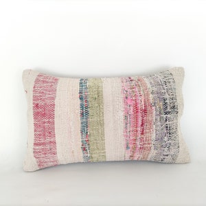May include: A rectangular pillow with a white background and colorful stripes in shades of pink, red, green, and blue.