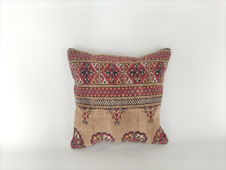 May include: A decorative pillow with a brown background and a red, black, and white geometric pattern.