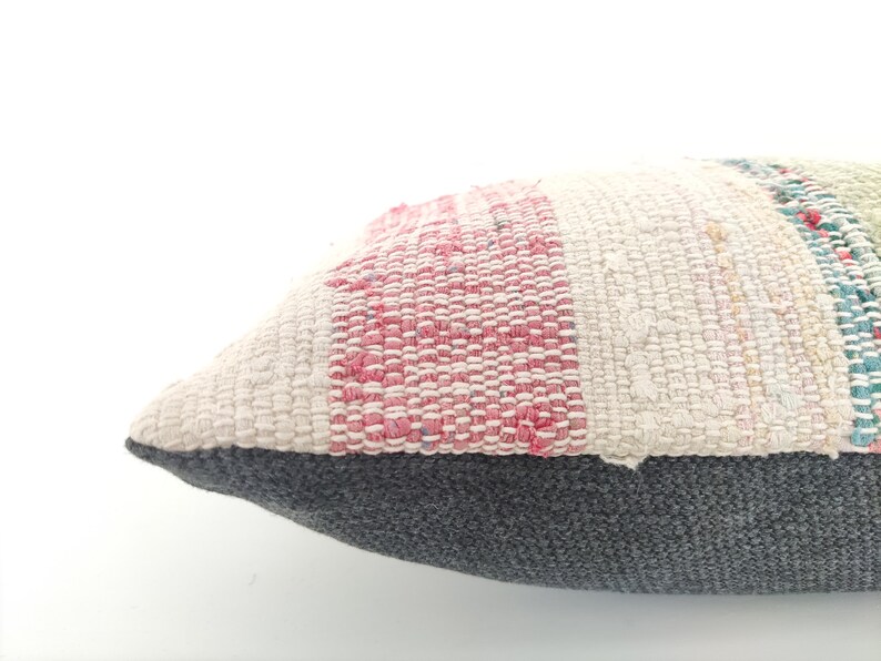 May include: A rectangular pillow with a striped pattern in shades of pink, white, and green. The pillow has a gray fabric backing.