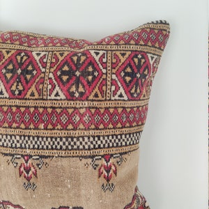 May include: A rectangular pillow with a brown background and a colorful geometric pattern in red, black, and yellow. The pillow is made of a soft, woven fabric.