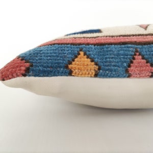 May include: A blue, pink, and yellow patterned throw pillow with a white backing.