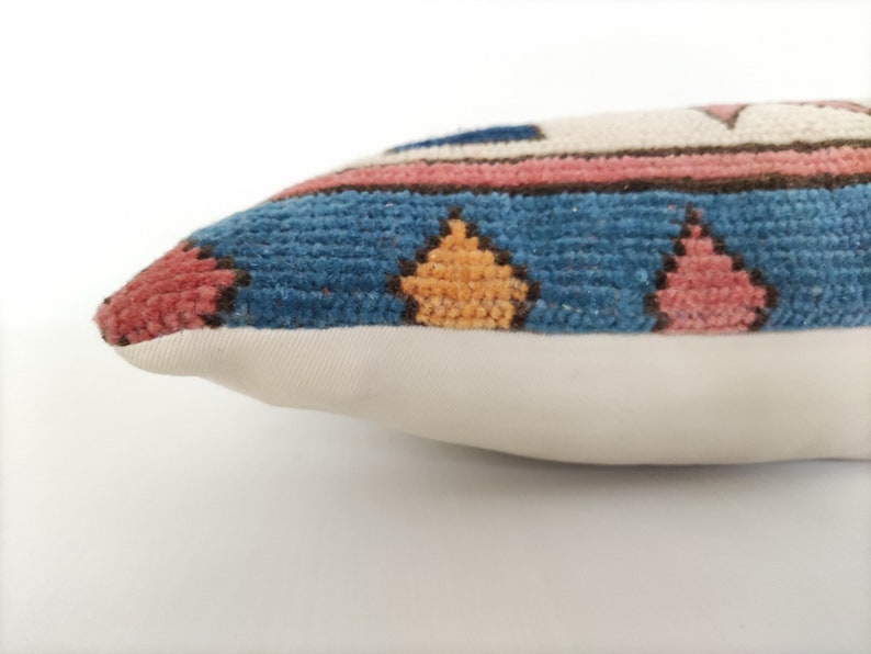 May include: A blue, pink, and yellow patterned throw pillow with a white backing.