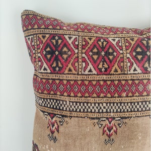 May include: A rectangular pillow with a brown, red, and black geometric pattern. The pillow has a fringe border and is made of a soft, woven fabric.