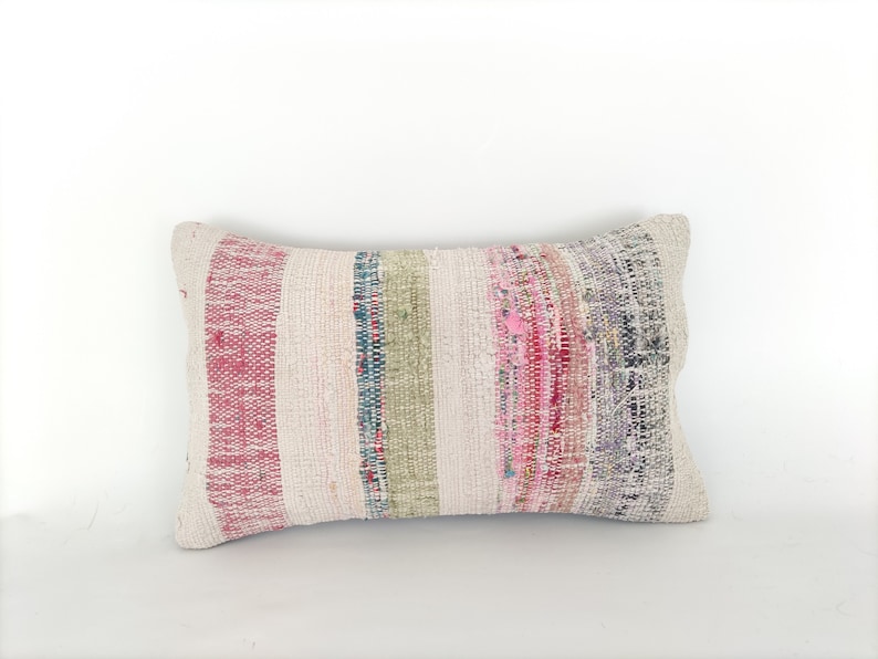 May include: A rectangular pillow with a white background and colorful stripes in shades of pink, red, green, and blue.