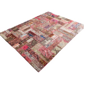May include: A patchwork rug made from various colorful fabrics in shades of red, pink, brown, and beige. The rug is made up of many small squares and rectangles, each with a different pattern.