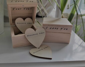 May include: A wooden box with the text "I Love You" and "Your Text" on the lid. The box contains three wooden heart-shaped tokens with the text "Housework Token" on each.