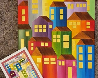 May include: A colorful painting of a city skyline with houses in various shades of red, yellow, blue, green, and purple. The houses are arranged in a geometric pattern, with windows that are outlined in gold. The painting is framed in a white frame.