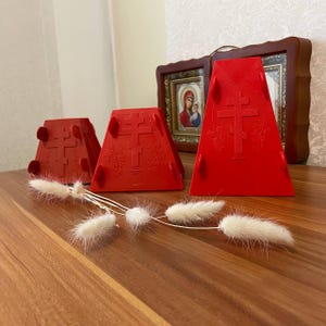 Pode incluir: Três porta-velas de plástico vermelho em forma de pirâmide com um design de cruz e as palavras "Слава Богу" em escrita cirílica.