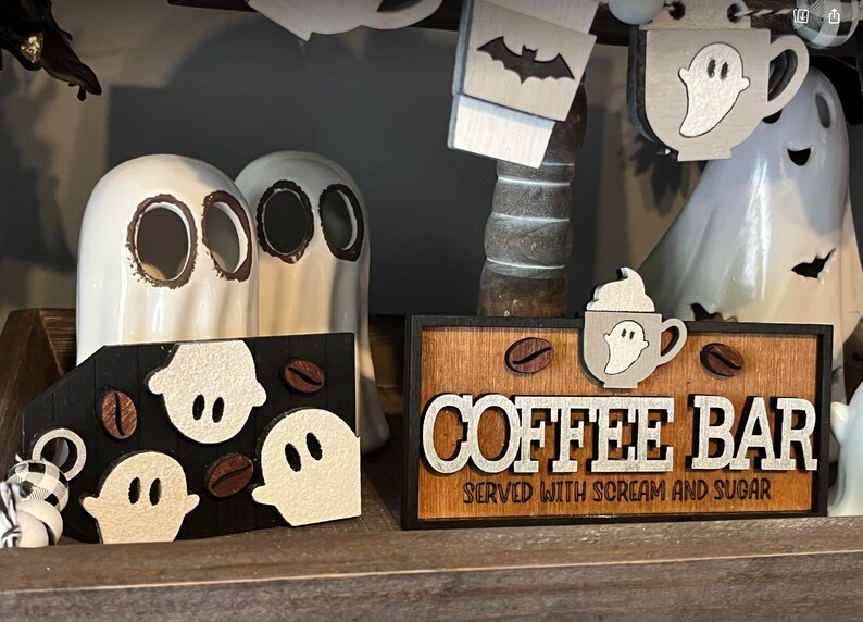 May include: A wooden sign with the text "COFFEE BAR SERVED WITH SCREAM AND SUGAR" in white letters. The sign is decorated with coffee beans and ghosts.