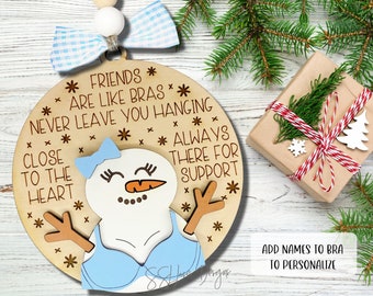 May include: Wooden Christmas ornament shaped like a snowman wearing a blue bra. The ornament has the text "Friends are like bras, never leave you hanging, close to the heart, always there for support".