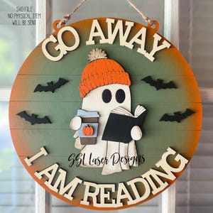 May include: A round wooden sign with the words "GO AWAY I AM READING". The sign features a ghost wearing an orange beanie and holding a book and a coffee cup. Black bat cutouts are scattered around the ghost. The sign is designed for Halloween.