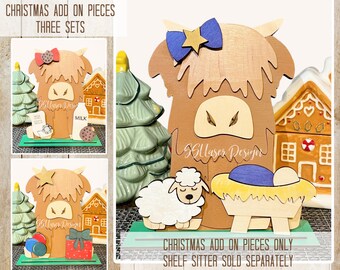 Könnte beinhalten: Drei Sets mit Weihnachts-Zusatzteilen für einen Holz-Highland-Cow-Regal-Sitzer. Die Sets beinhalten einen Weihnachtsbaum, ein Lebkuchenhaus, ein Geschenk, Ballons, einen Stern, ein Schaf, eine Krippe und ein Jesuskind. Der Text "Gllasys Design" ist auf der Kuh sichtbar.