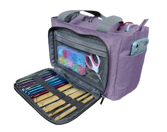 May include: A purple knitting bag with a zippered compartment that holds knitting needles and crochet hooks. The bag has a clear plastic pocket for small items and a side pocket for a phone.