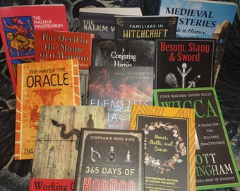Puede incluir: Una colección de libros con títulos como "365 Days of Hoodoo", "Wicca" y "The Malleus Maleficarum". Los libros, de varios colores y tamaños, presentan texto e ilustraciones en sus portadas. Los libros están dispuestos sobre una superficie estampada.